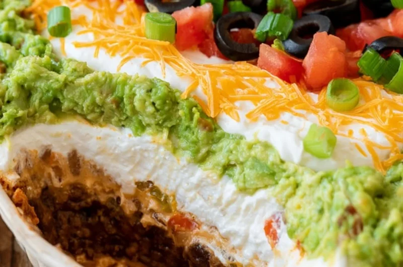 Delicious 7 layer dip served in a bowl, featuring layers of beans, guacamole, salsa, and cheese.