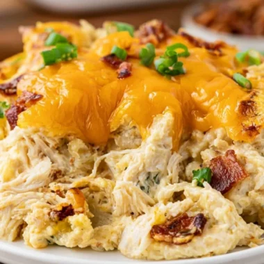 Cozy Crack Chicken Casserole topped with cheese and herbs in a baking dish