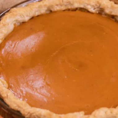 Delicious homemade sweet potato pie topped with whipped cream and spices.