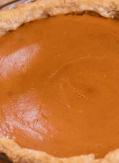 Delicious homemade sweet potato pie topped with whipped cream and spices.