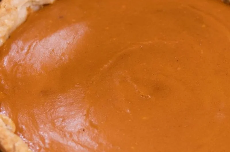 Delicious homemade sweet potato pie topped with whipped cream and spices.