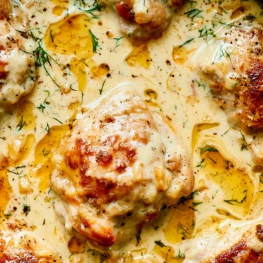 Creamy oven baked chicken thighs on a plate garnished with herbs