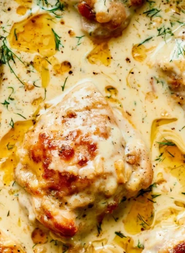 Creamy oven baked chicken thighs on a plate garnished with herbs