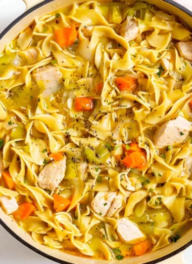 Bowl of homemade Dutch Oven Chicken Noodle Soup with fresh ingredients.