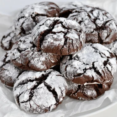 Easy chocolate crinkle cookies dusted with powdered sugar on a baking tray.